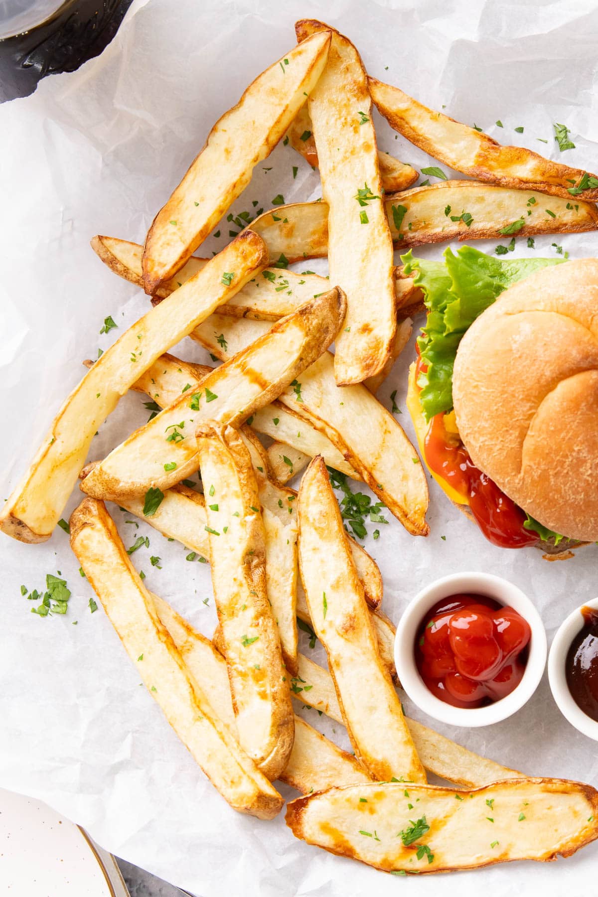 Basket of air fryer French fries with crisp edges and tender insides served with condiments and a burger