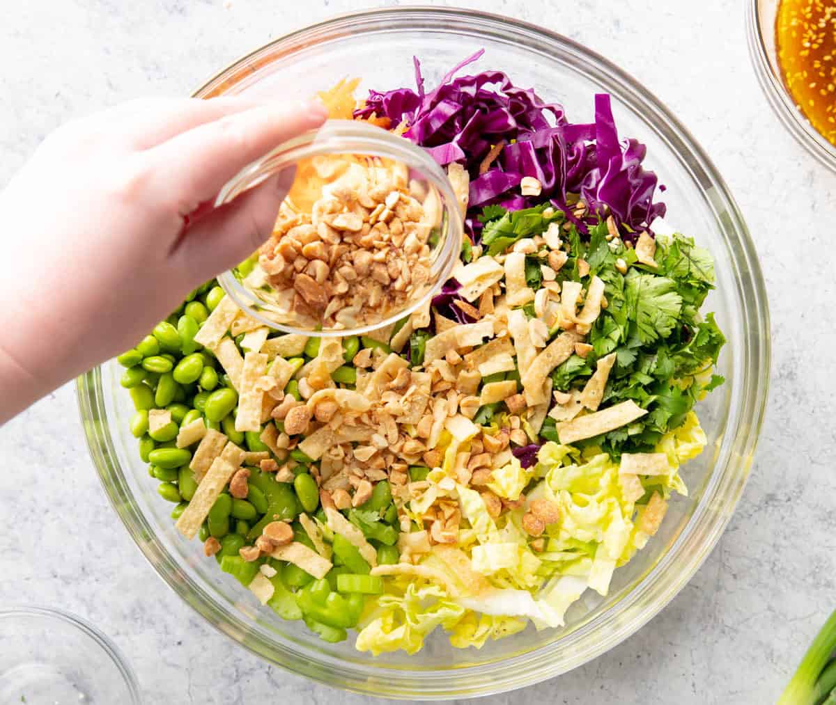 Photo showing How to make an Asian Salad – sprinkling chopped honey peanuts over salad