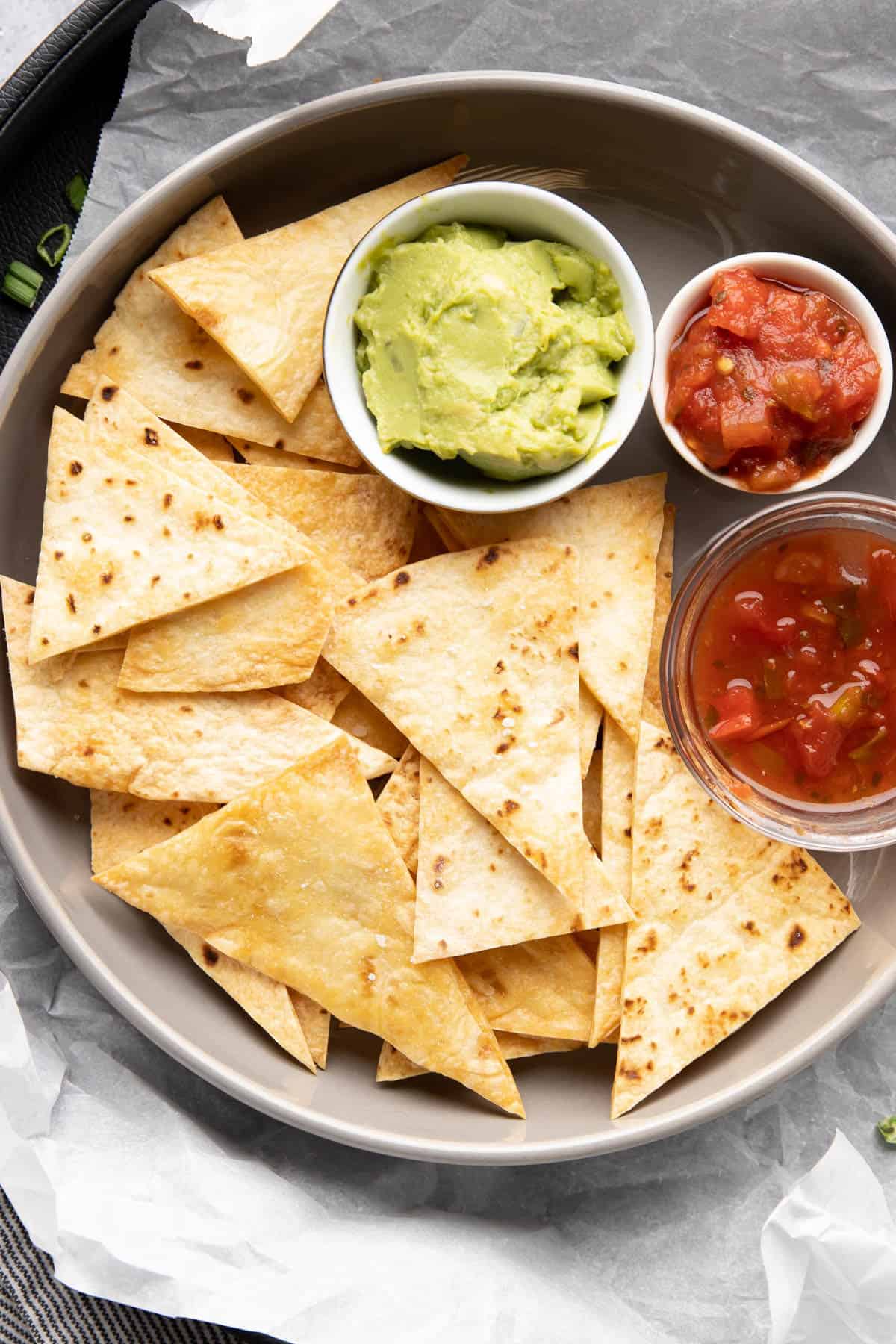 Plate full of baked tortilla chips and assorted dips