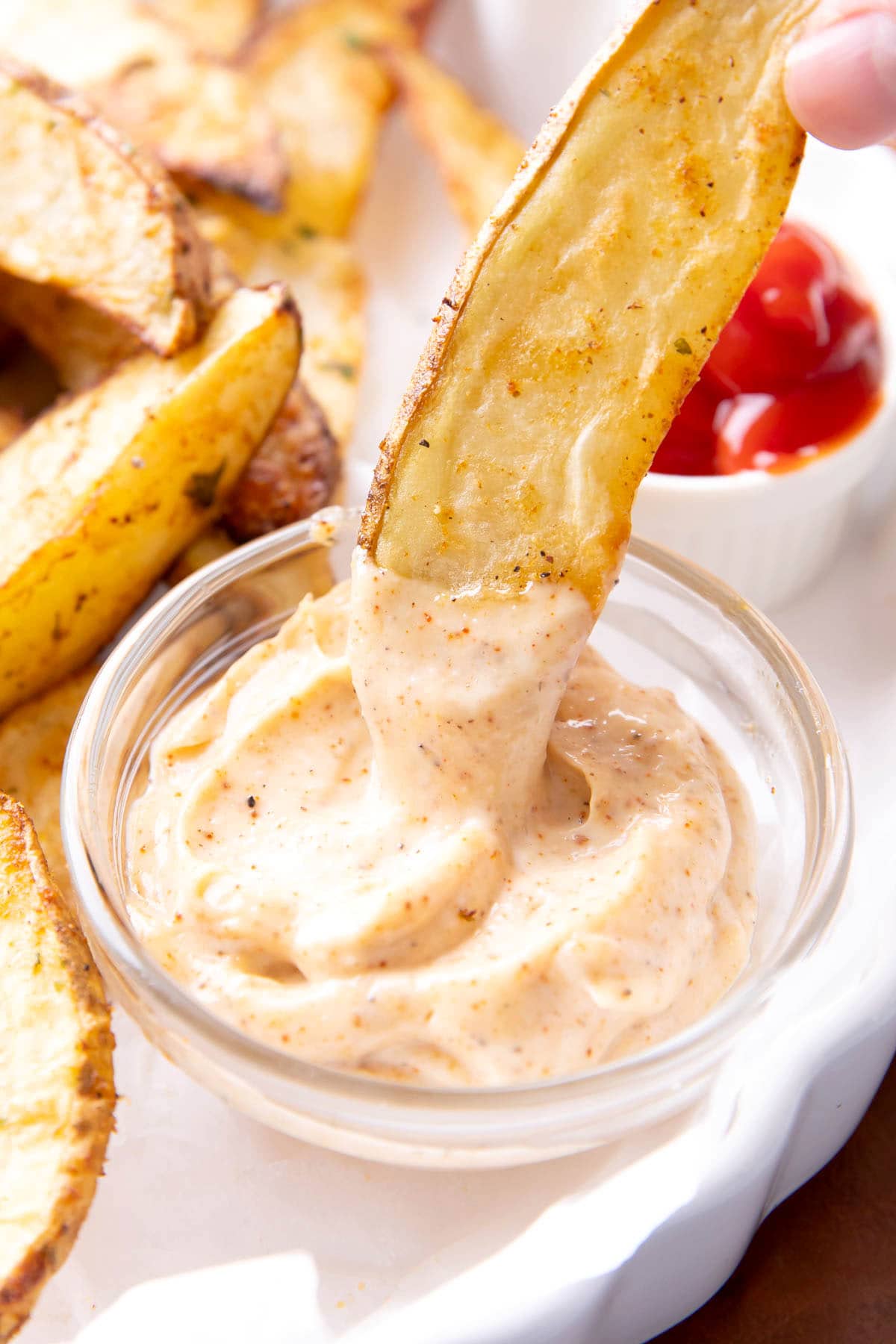 Dipping a potato wedge into chipotle aioli