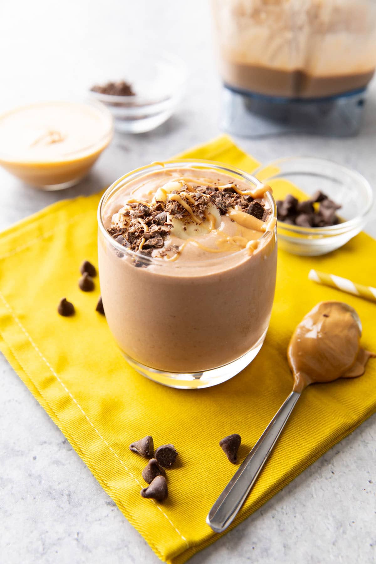 Chocolate peanut butter banana smoothie served in a glass cup topped with chocolate shavings and peanut butter drizzle