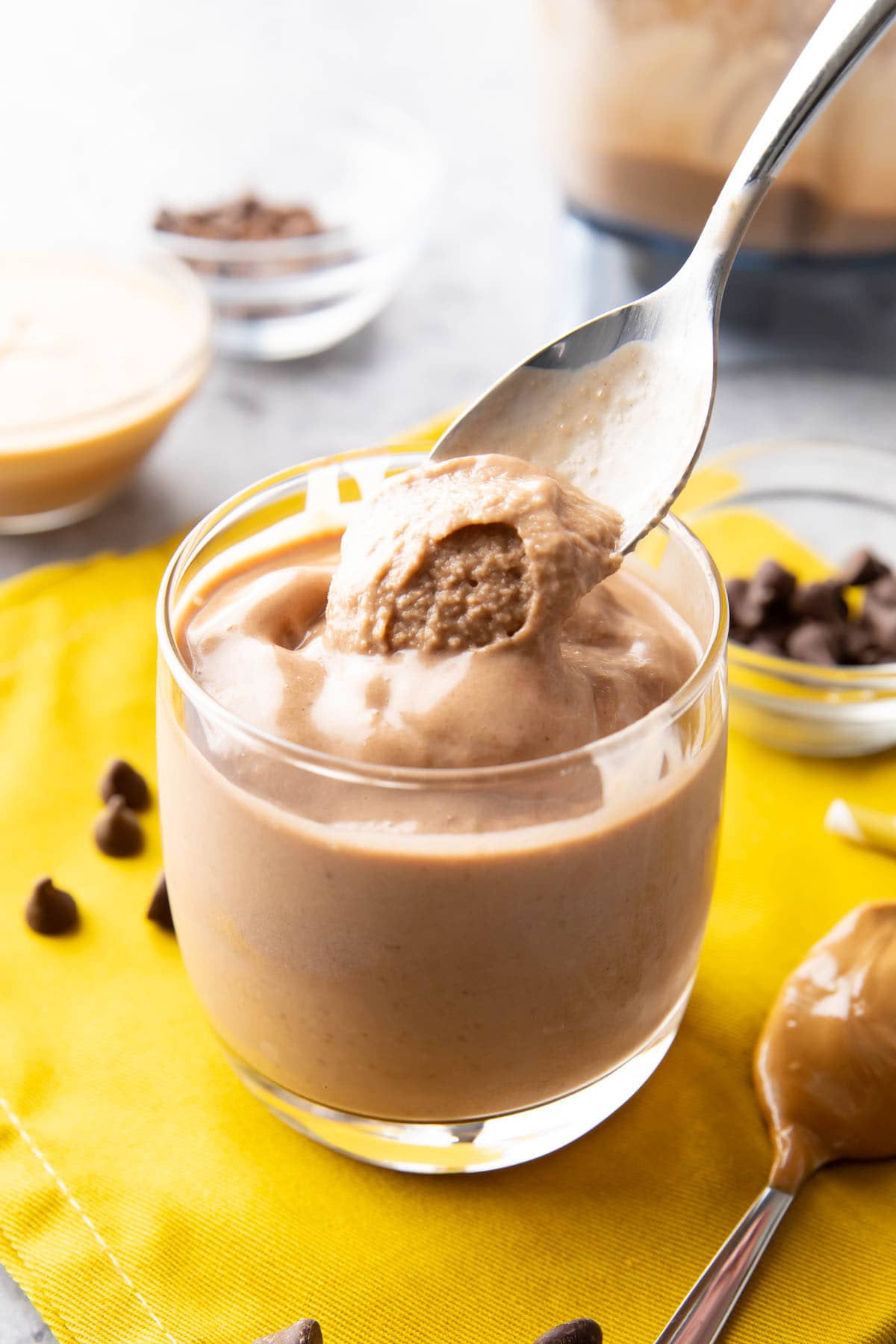 Dipping a spoon into this chocolate peanut butter banana smoothie to show the thick texture