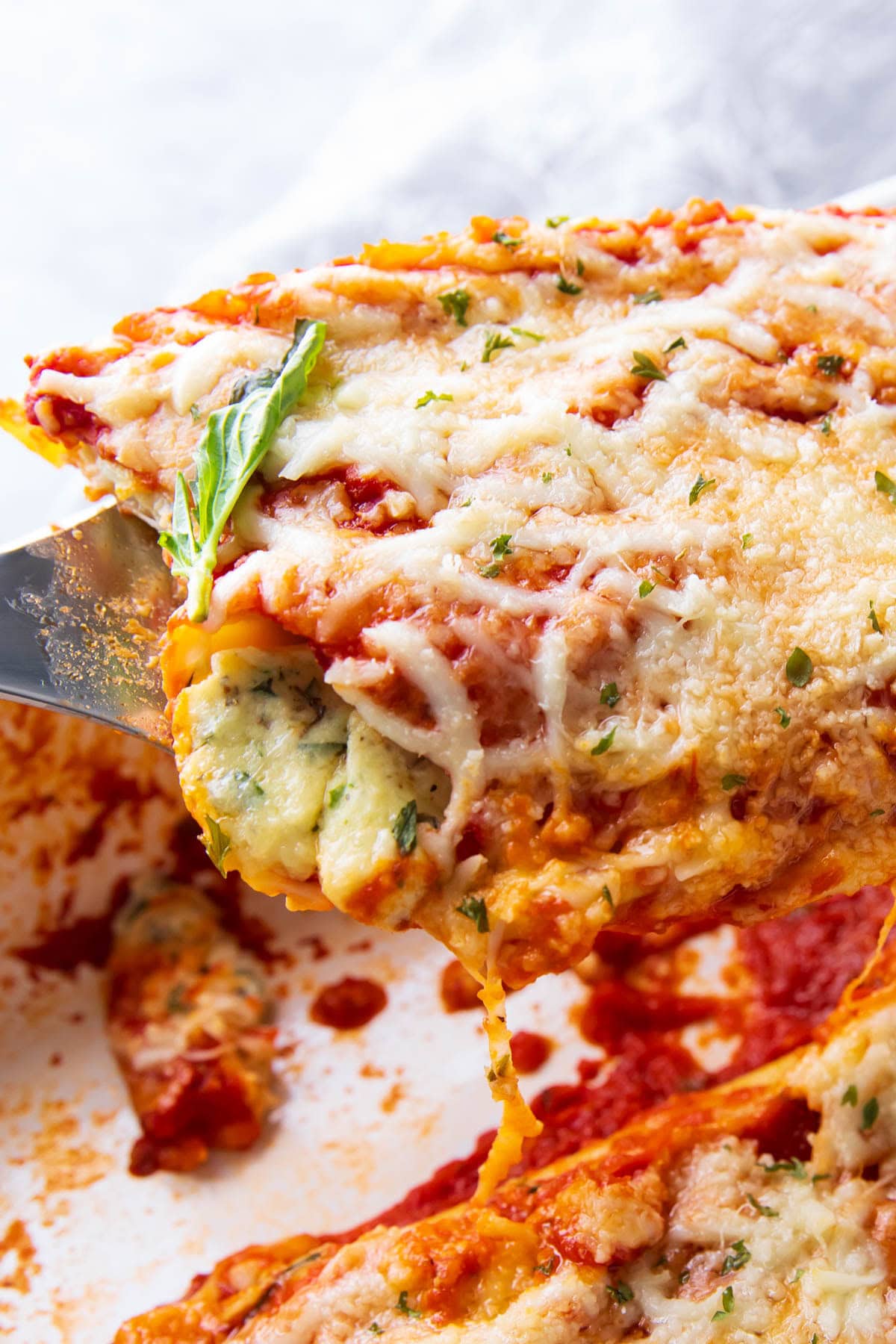 Close up of a spatula full of this easy manicotti recipe stuffed with ricotta cheese.