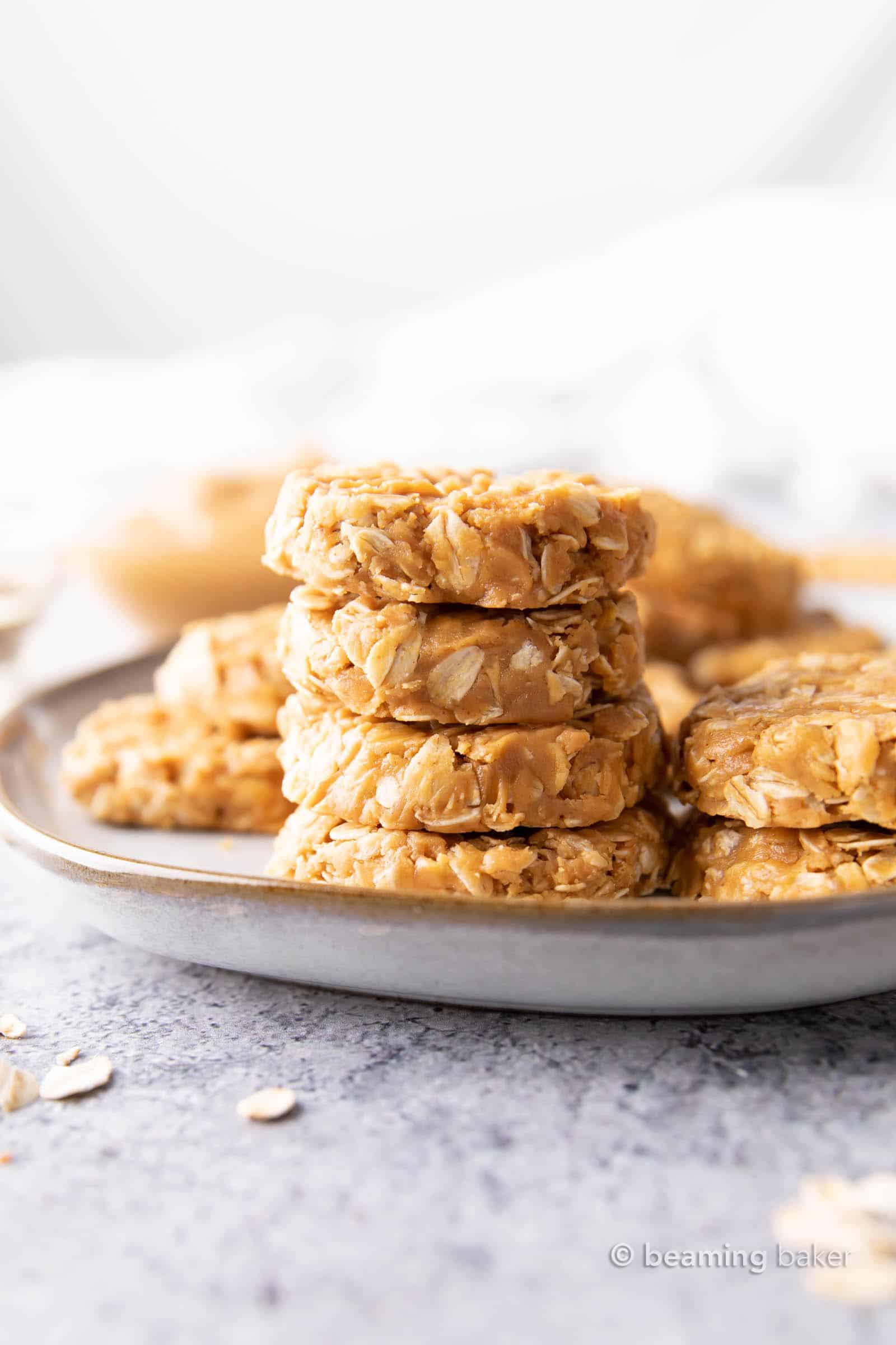 Stack of peanut butter no bake cookies on a gray plate with more cookies surrounding them.