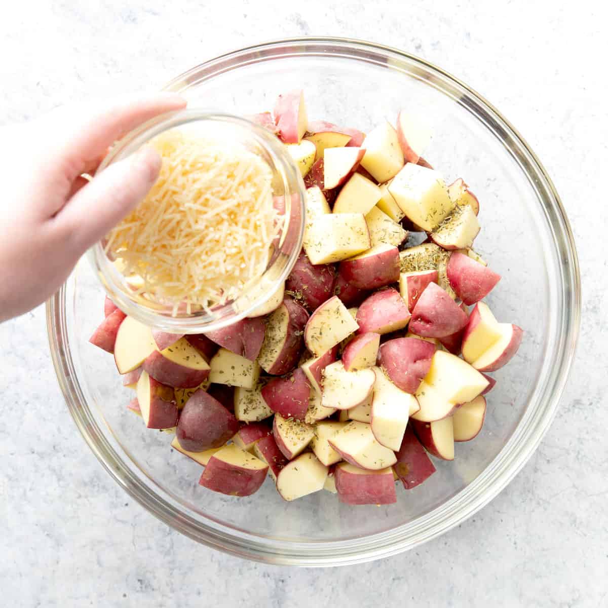 Two photos showing how to make garlic roasted potatoes – adding parmesan to bowl