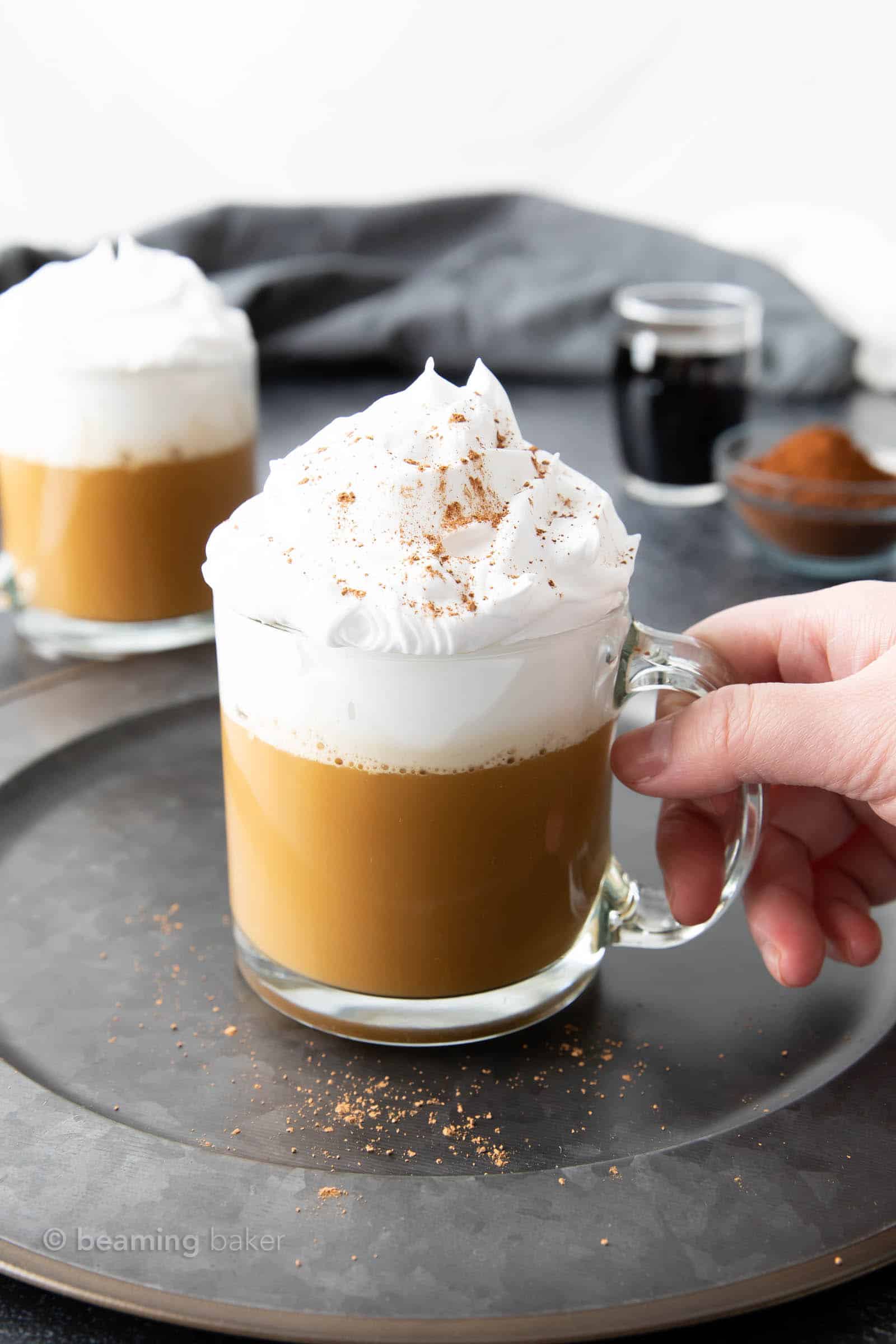 hang grabbing glass mug of hot white russian topped with cinnamon