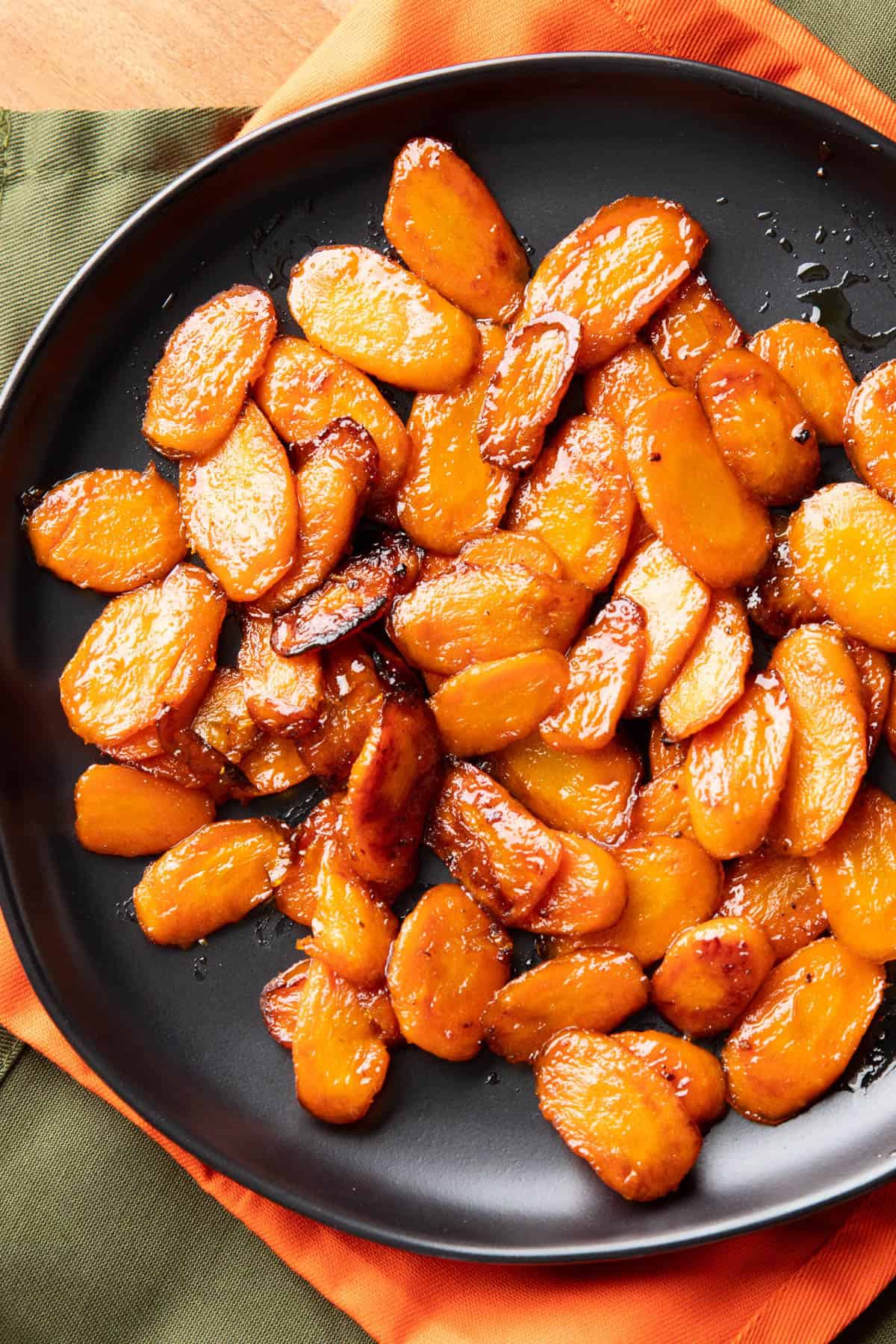 closeup photo of maple glazed carrots on a black plate