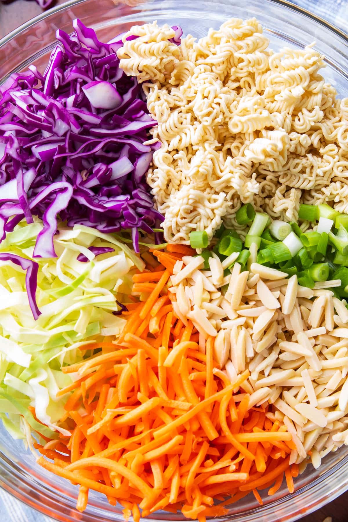 Close up of crisp and colorful cabbage, crunchy ramen pieces, flavorful green onions and more toppings