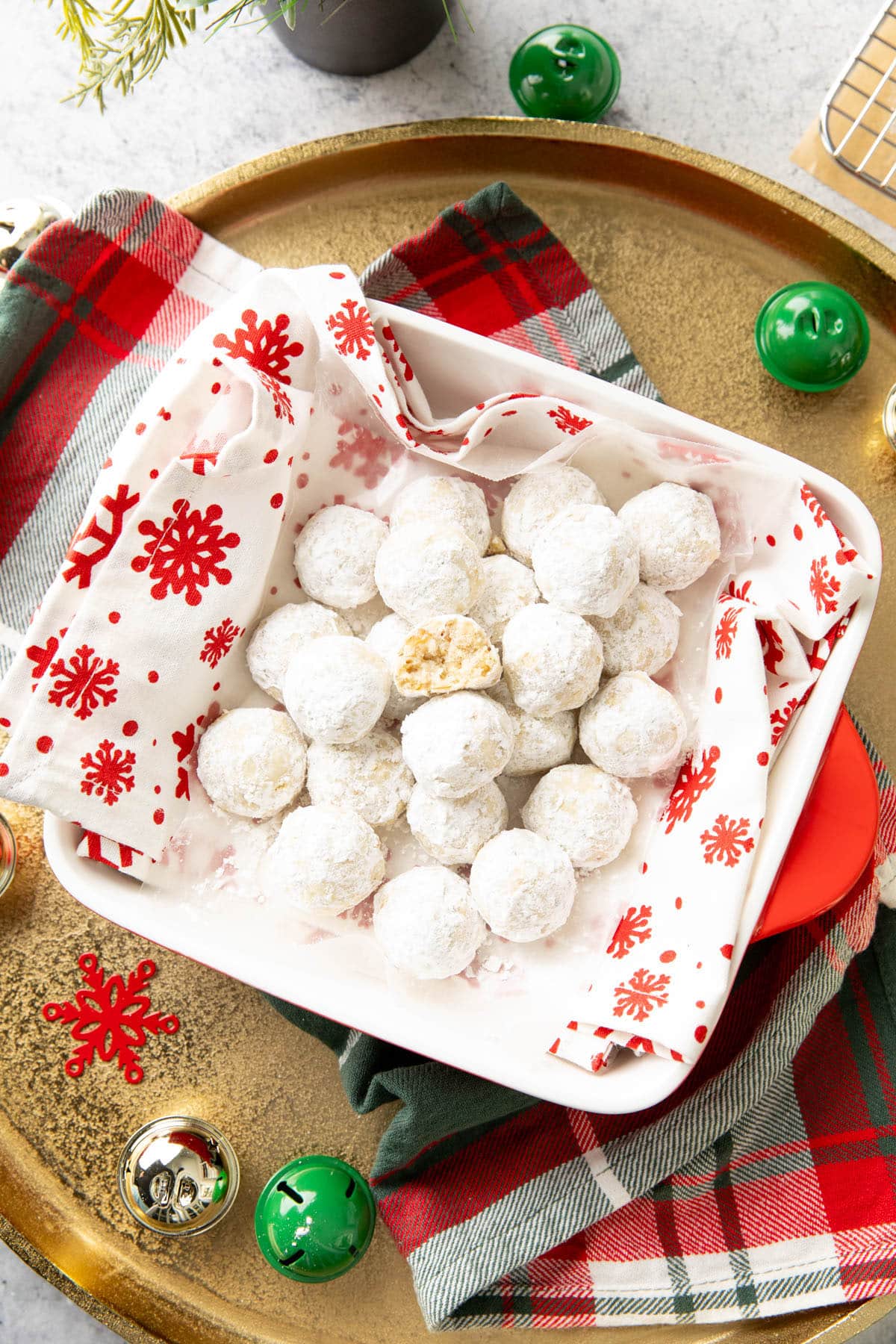 Overhead photo of Christmas treats wrapped in a red snowflake napkin on a gold tray
