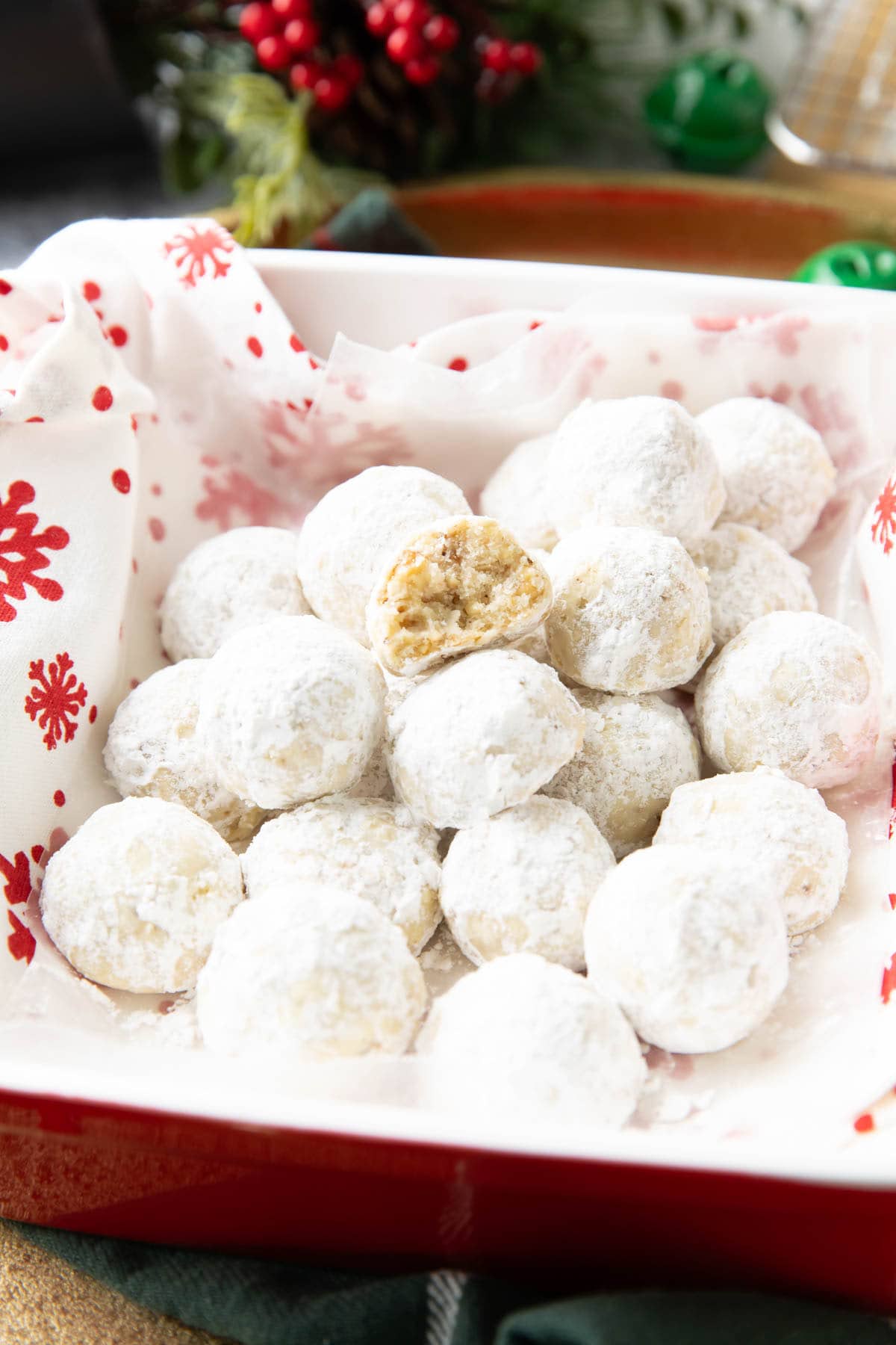 Bitten Cookie on a stack of Snowball Cookies in a serving dish