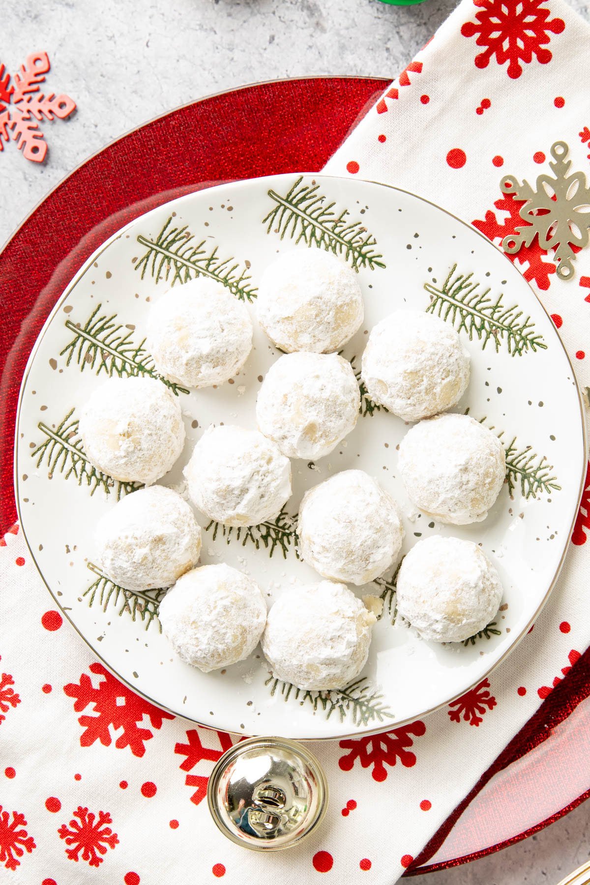 buttery pecan snowball cookies recipe on a tree-lined plate with ornaments and snowflakes