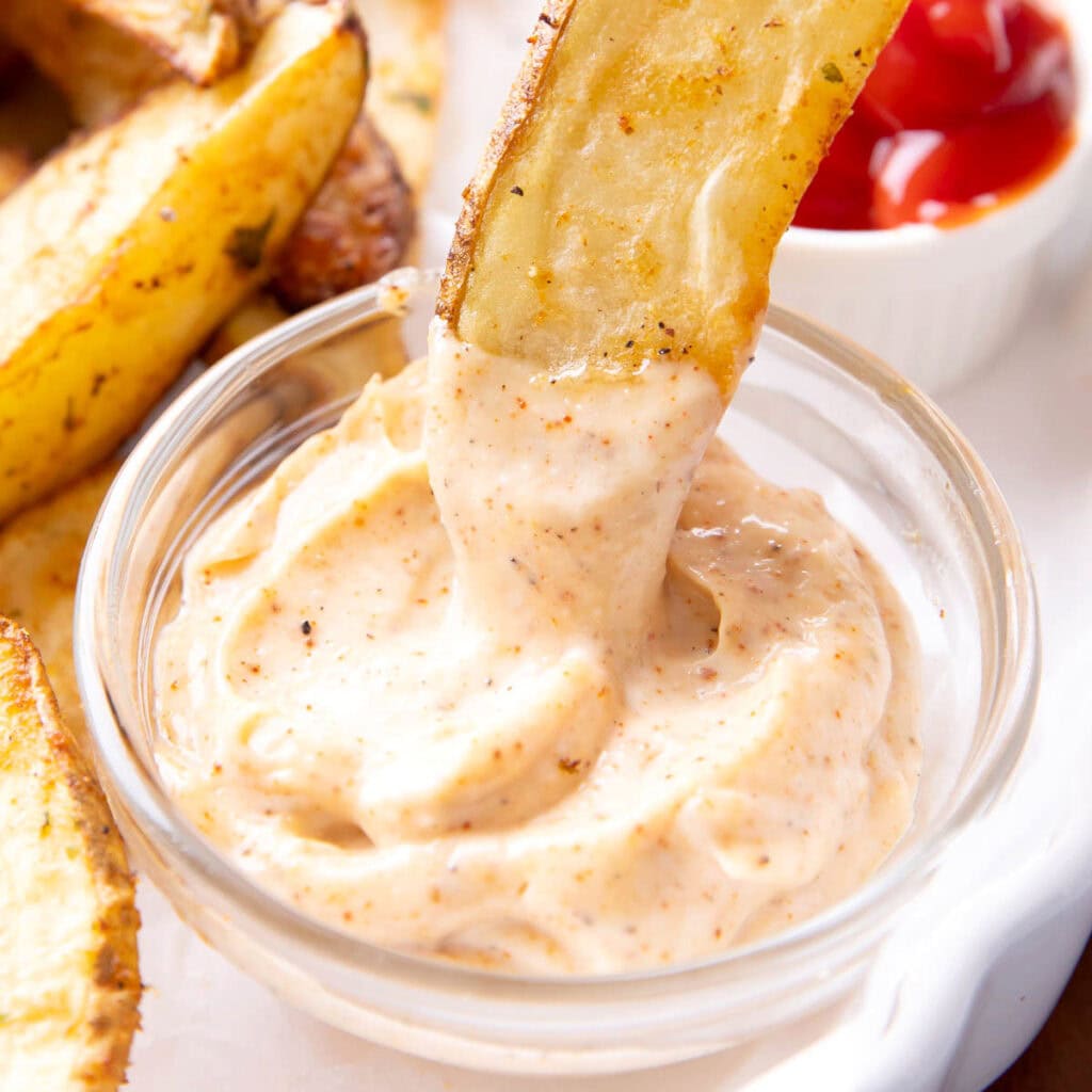 dipping an appetizer into a small bowl of chipotle aioli